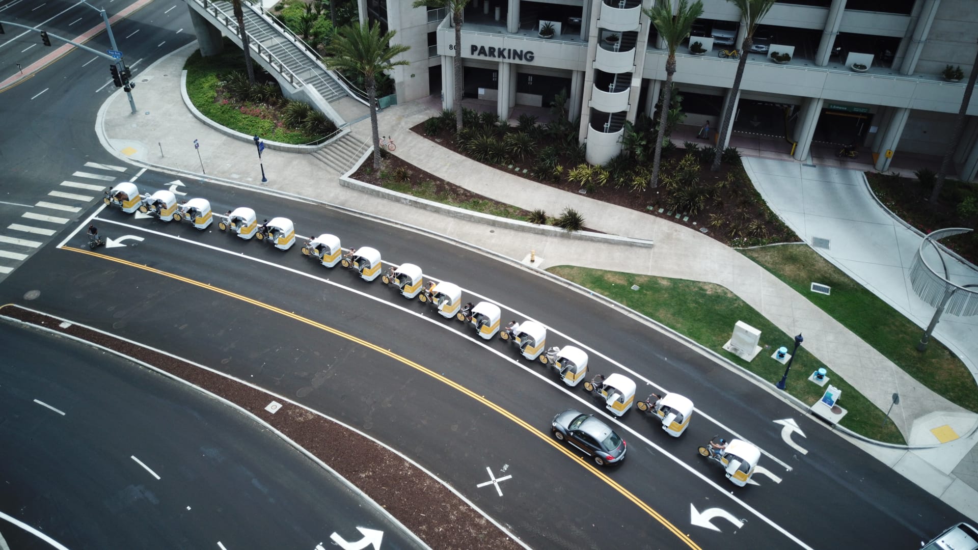 Aerial view of a branded pedicab fleet in a line through downtown San Diego