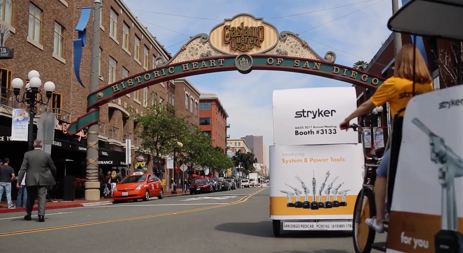 Stryker branded pedicab riding under Gaslamp Quarter archway San Diego