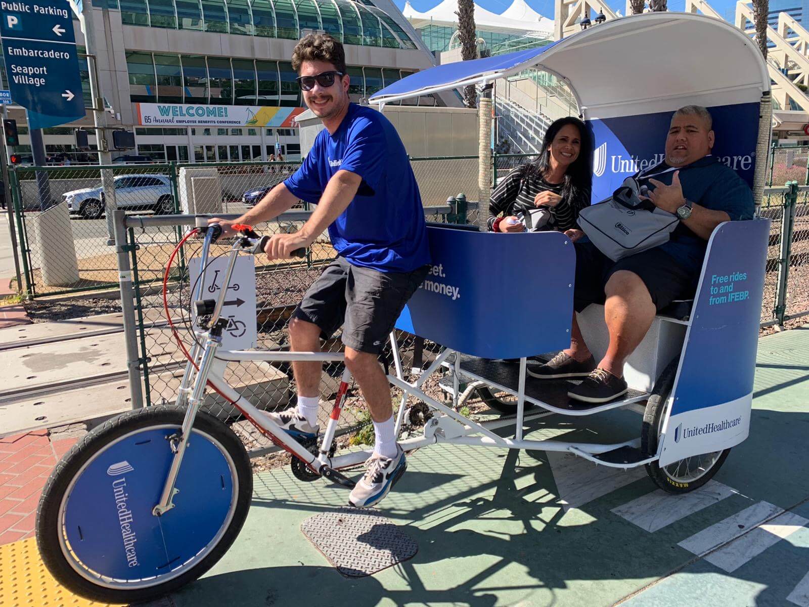 Smiling pedicab driver with passengers at Embarcadero Employee Benefits Conference