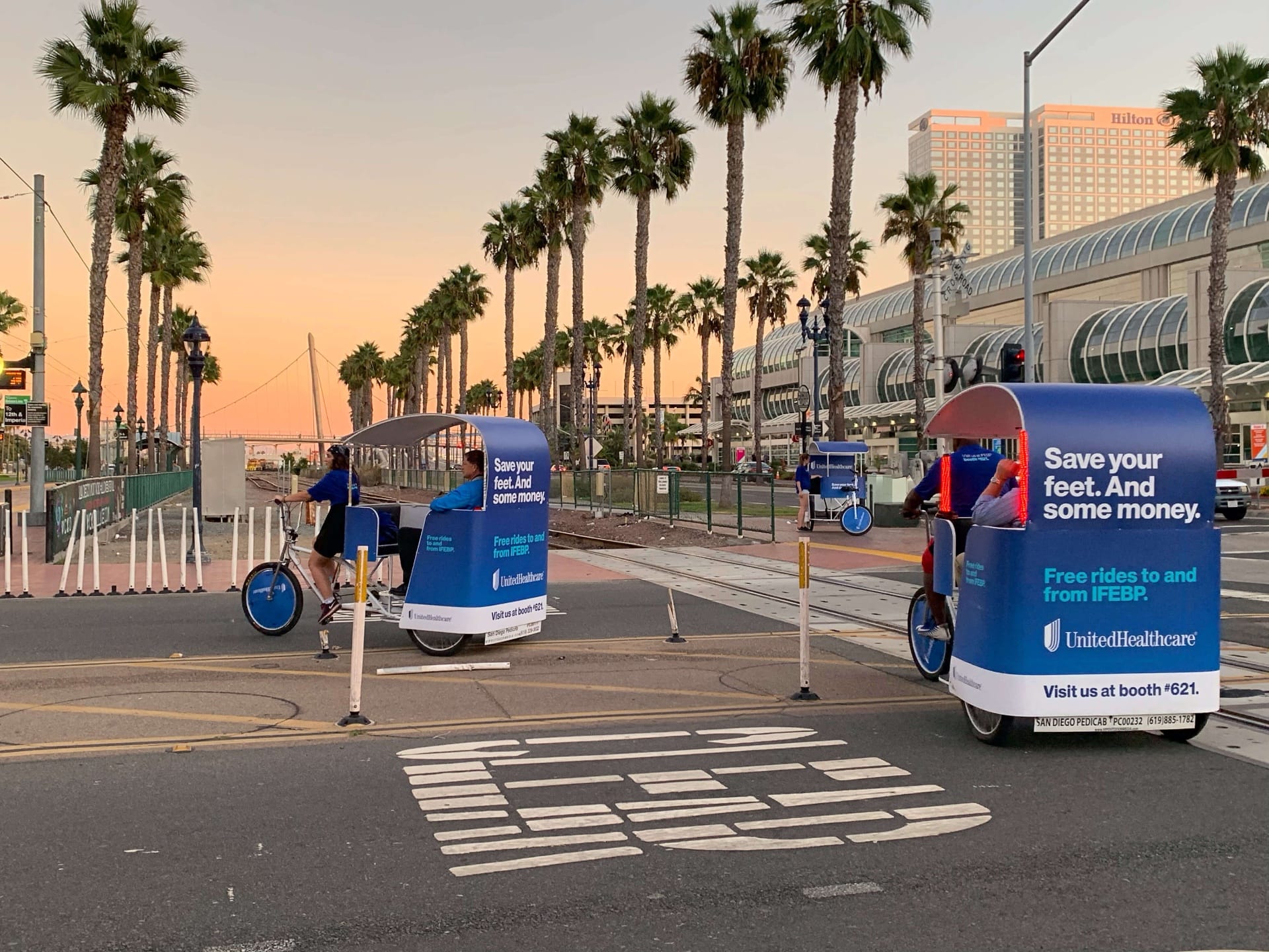 UnitedHealthcare pedicab fleet at sunset with Convention Center and palm trees